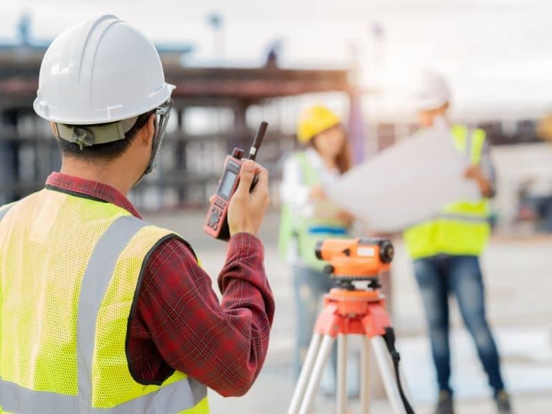 Land surveyor using equipment at a construction site for different types of land survey projects
